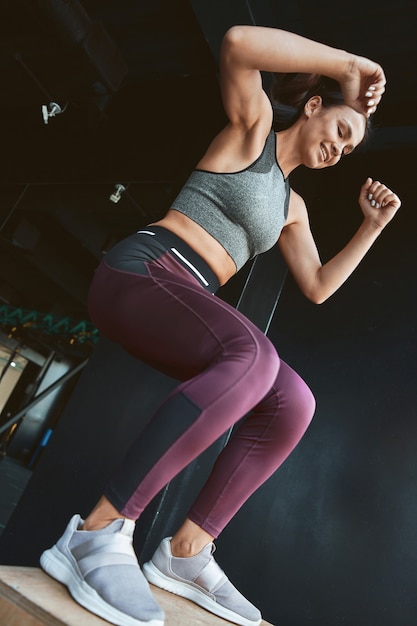 Foto os melhores exercícios para queima de calorias, vista inferior de uma mulher forte e atlética em roupas esportivas, fazendo uma caixa