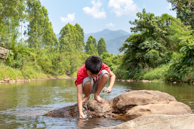 Os meninos asiáticos estão alimentando os peixes no fluxo.