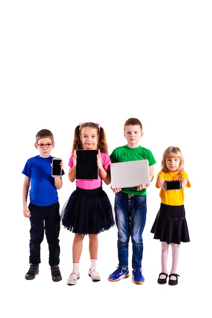 Os meninos e meninas com roupas coloridas em pé com dispositivos isolados em um fundo branco. o conceito de tecnologia de ponta