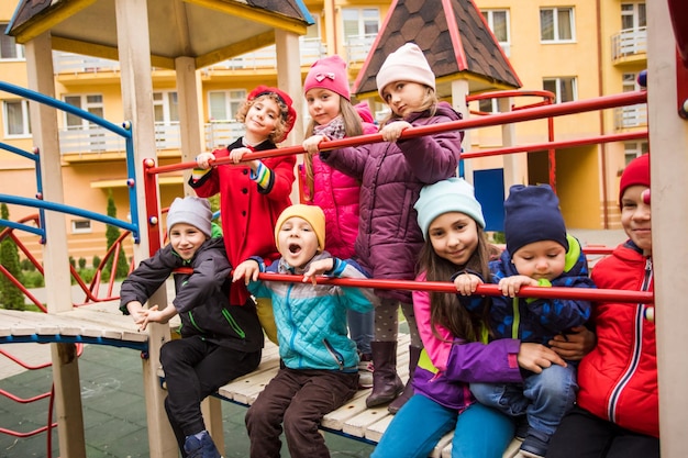 Os meninos e meninas no playground no outono As crianças felizes estão juntas e posando para a câmera