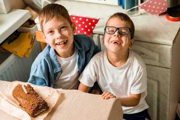 Os meninos estão comemorando seu aniversário. parafernália de aniversário das crianças. Irmãos cobertos de bolo em seus rostos. festa de familia em casa