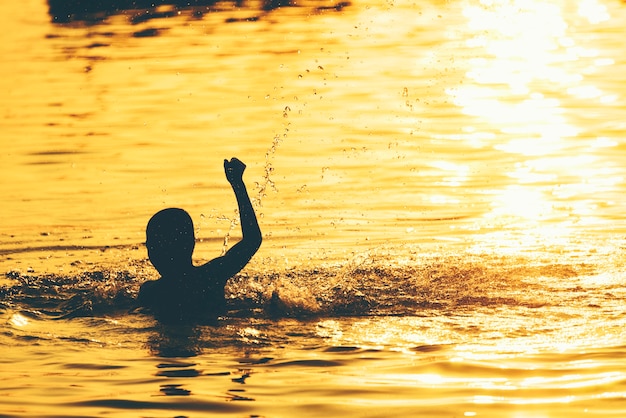 Os meninos estão jogando a água no por do sol