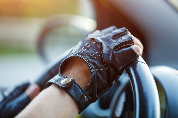 Os motoristas usam luvas de couro, dirigindo uma mulher em movimento segurando o volante em luvas de corrida