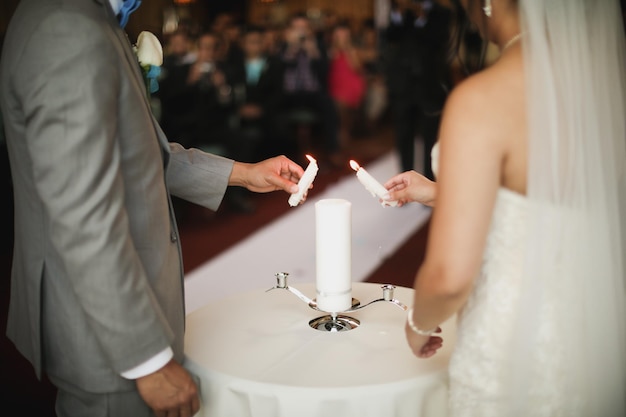 Os noivos acendem uma vela em sua cerimônia de casamento.