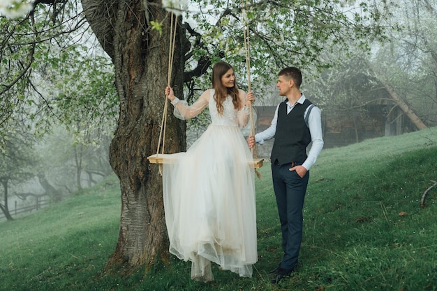 Os noivos andam de balanço de corda no jardim. casamento na floresta.