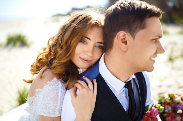 Os noivos bonitos apreciam-se caminhando ao longo da praia. casal jovem romântico feliz comemorando seu casamento