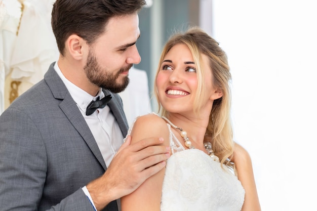 Os noivos pares de sorriso caucasiano e abraçam no estúdio do casamento.