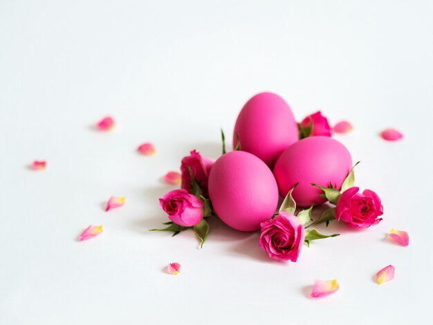 Os ovos da páscoa decorativos e as rosas cor-de-rosa põem ovos da páscoa no fundo claro. cartão de férias.