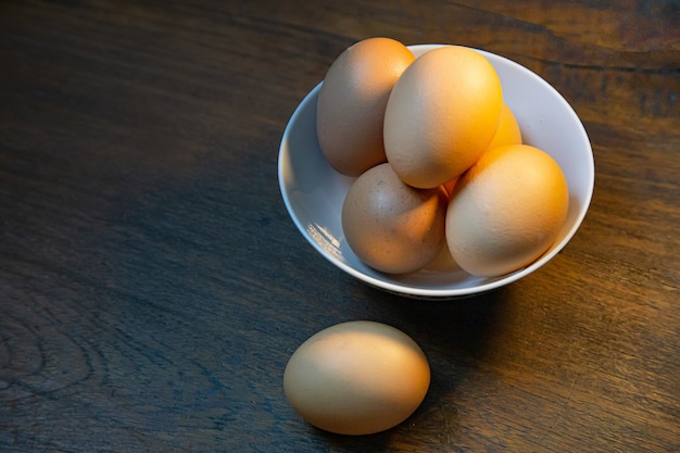 Os ovos na tigela na mesa de madeira para o conteúdo alimentar.