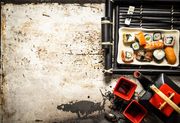 Foto os pãezinhos e o sushi em uma bandeja com chá de ervas em fundo rústico