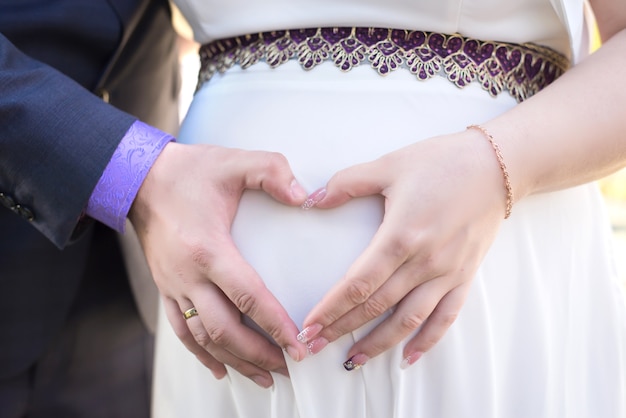 Os pais de mãos dadas no coração barriga