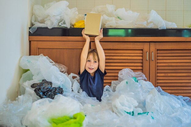 Os pais do menino usaram muitos sacos plásticos que encheram toda a cozinha Menino mostra um saco de papel Conceito de lixo zero O conceito do Dia Mundial do Meio Ambiente