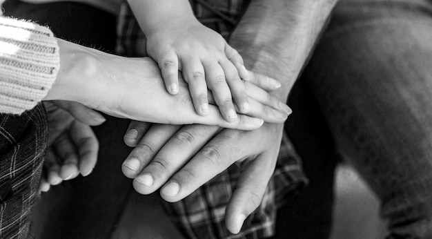 Os pais seguram as mãos do bebê Fechamento da mão do bebê nas mãos dos pais Conceito de unidade apoio proteção felicidade Preto e branco
