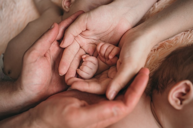 Foto os pais seguram suavemente as mãos das crianças pequenas closeup da mão do bebê e os pais se preocupam com t ...