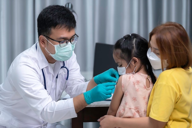 Os pais trazem a filha ao médico para vacinação contra a gripeA mãe trouxe a criança ao médico na clínica