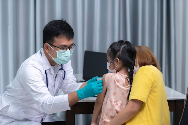 Os pais trazem a filha ao médico para vacinação contra a gripeA mãe trouxe a criança ao médico na clínica