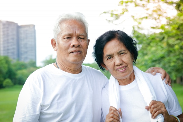 Os pares asiáticos mais velhos exercitam-se no parque.