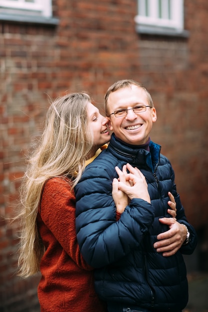 Os pares de amantes andam lentamente na manhã fresca do outono nas ruas de um lubeque (alemanha). o indivíduo guarda sua esposa. férias, outono, feriado, turismo: conceito.