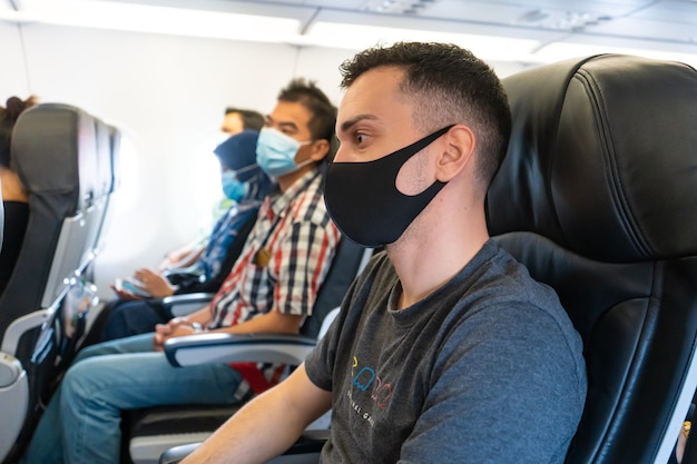 Os passageiros do avião usam máscaras médicas no rosto. viagem aérea durante a pandemia do coronavírus. requisitos das companhias aéreas.