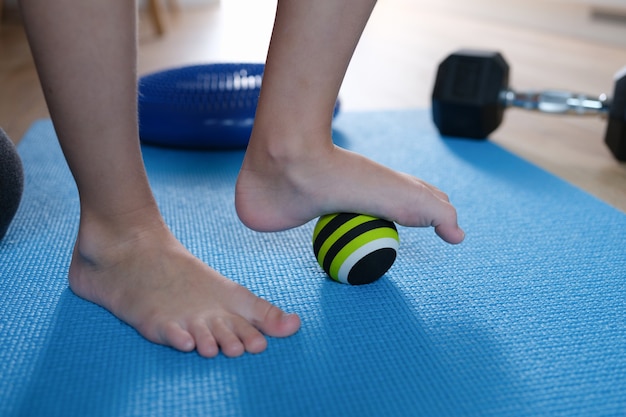 Os pés da criança estão em uma pequena bola esportiva em casa, close-up