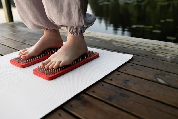 Os pés da mulher estão em pranchas com unhas Yoga ao ar livre Tábua de unhas Natureza