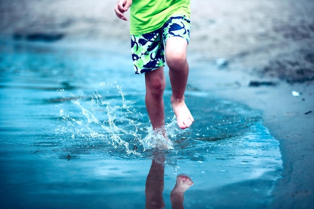 Os pés das crianças correm pela água pulverizando água