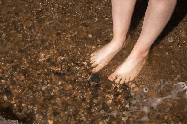 Os pés de um homem lavados pelas ondas Fim de semana de relaxamento das férias de verão