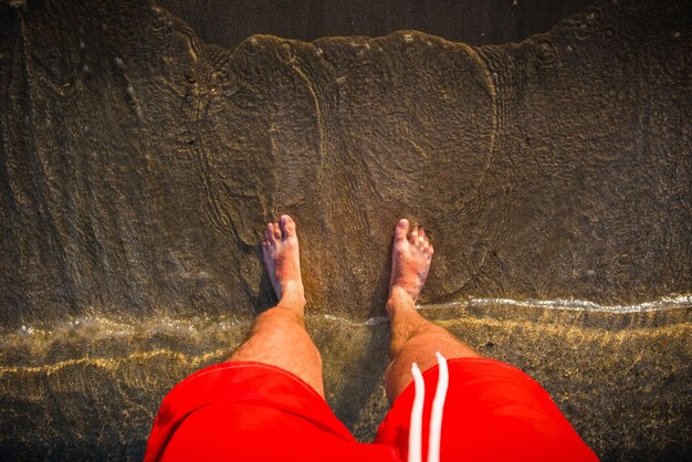 Foto os pés do homem na areia as ondas se aproximam da praia
