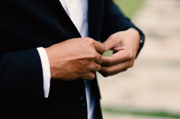 Os preparativos para o casamento dos homens têm as mãos arrumando as roupas antes da cerimônia