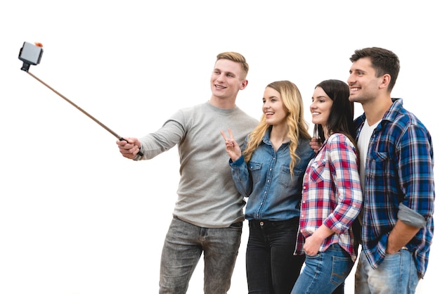 Os quatro amigos felizes fazem uma selfie no fundo branco