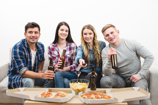 Os quatro felizes assistem tv com uma pizza e uma cerveja no fundo branco