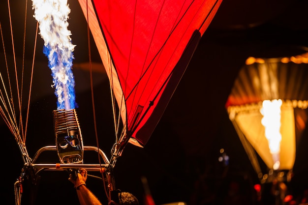 Os queimadores em um balão de ar quente disparando, enviando uma explosão de gás inflamado em balões festival noite