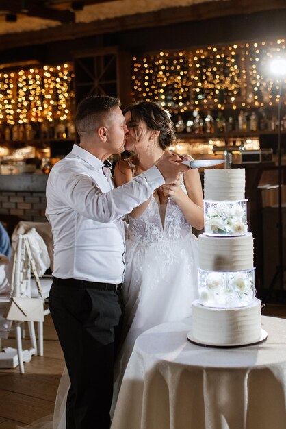 Os recém-casados cortam e provam felizmente o bolo de casamento.