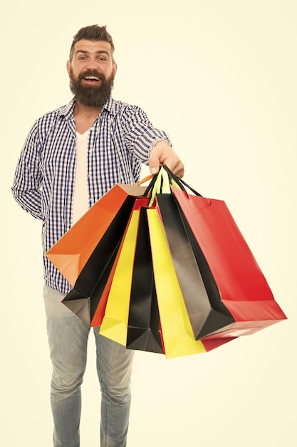 Os sacos estão cheios Feliz comprador hipster segurando sacos de compras isolados em branco Homem barbudo sorrindo com sacos de papel depois da venda sazonal Carregando compras de férias em sacos coloridos