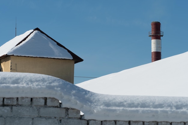 Os telhados dos edifícios estão cobertos de neve e gelo após uma grande queda de neve Enormes pingentes de gelo pendem das fachadas dos edifícios A queda de pingentes traz um perigo para a vida das pessoas