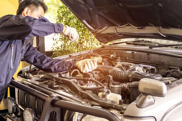 Os trabalhadores do reparo do carro puxam o medidor de nível de óleo do carro para verificar o centro de serviço de reparo do carro