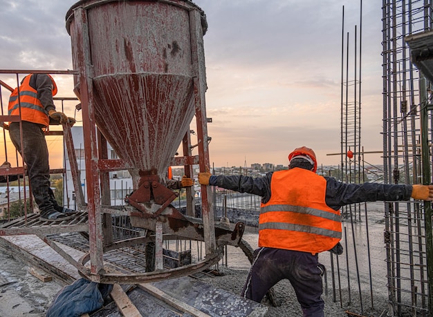 Os trabalhadores em um telhado de infraestrutura de construção com máquinas e ferramentas Despejando concreto em um molde