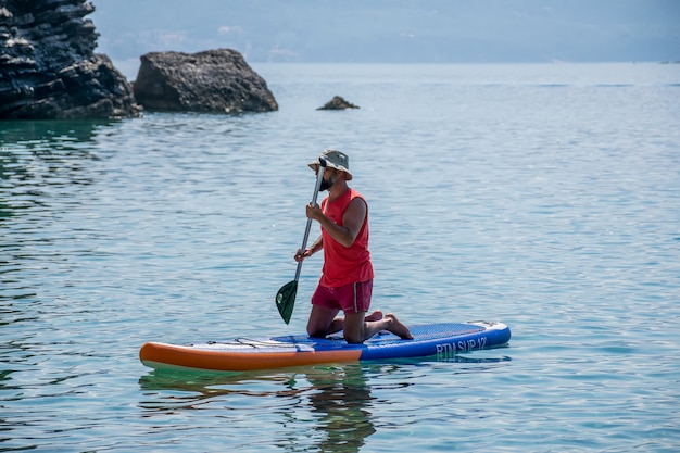 Os turistas estão empenhados em remar no tabuleiro (sup) na superfície do mar calmo.