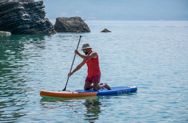 os turistas estão envolvidos no remo a bordo (SUP) na superfície do mar calmo.