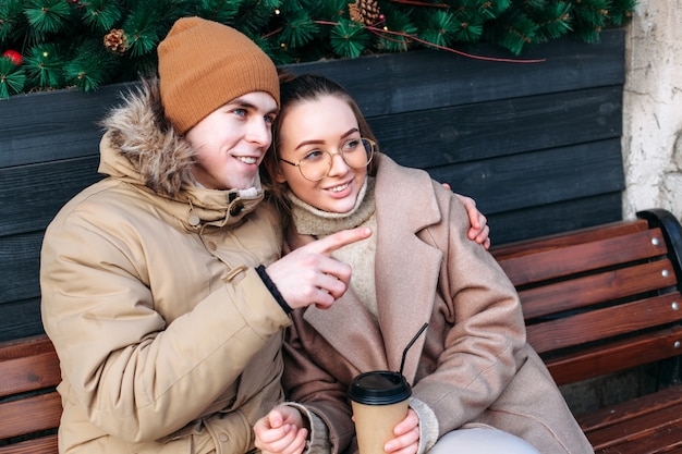 Os turistas se divertem juntos no inverno na rua sentado no banco, bebendo café