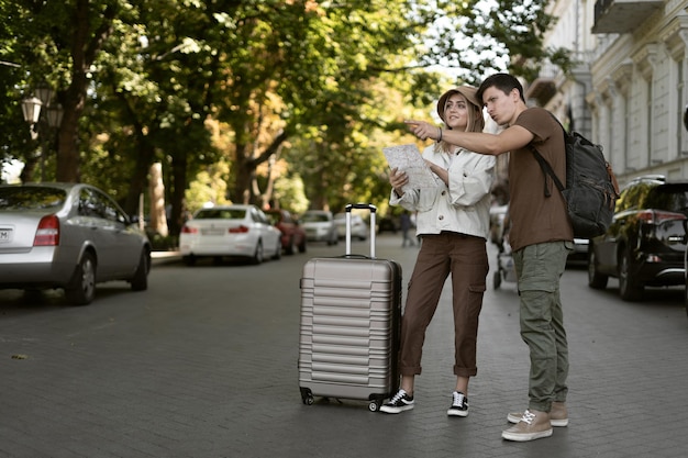 Foto os viajantes europeus adoram o casal usando um mapa local em um dia ensolarado. levanta a mão indica um lugar vazio. viagem de lua de mel, turismo europeu ou conceito de viagem de férias