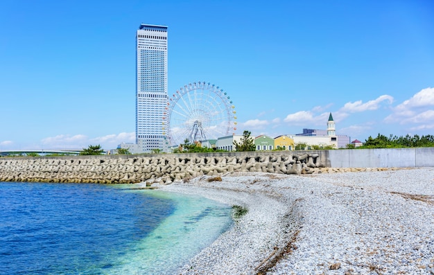 Osaka, japão - 10 de maio de 2018: praia de mármore branco artificial ao longo da costa da cidade de rinku, vendo o edifício da torre do portão de rinku e a roda gigante