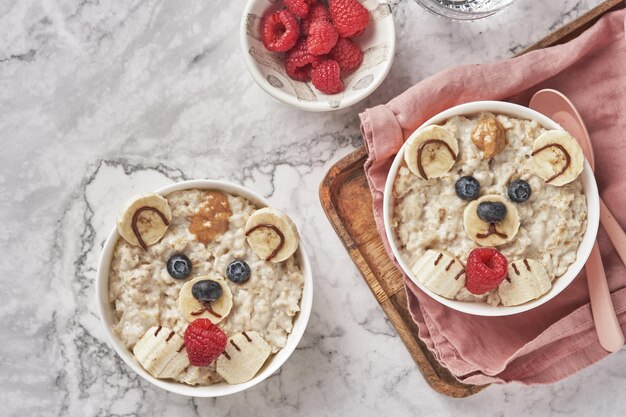 Oso de gachas de avena con plátano y bayas idea de arte de comida divertida para niños comida vista superior