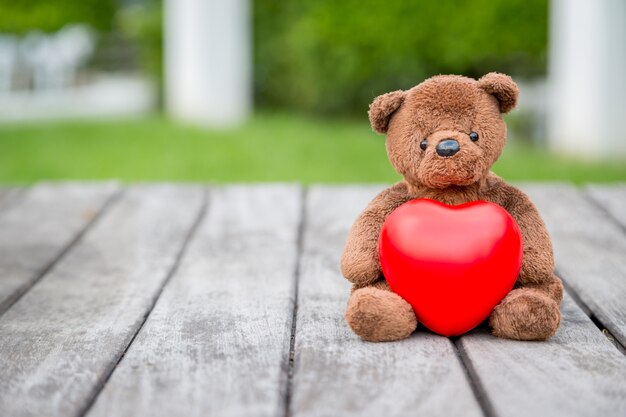 Oso pardo y corazón rojo con fondo de madera vieja para cuidar a tu amor