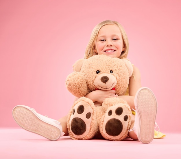 Oso de peluche amor niña y retrato con un juguete suave con felicidad y cuidado de los juguetes en un estudio Fondo rosa aislado y una niña joven que se siente feliz alegría y alegre con un amigo relleno