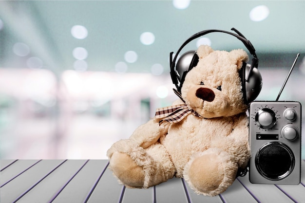 Oso de peluche con auriculares y radio en la mesa