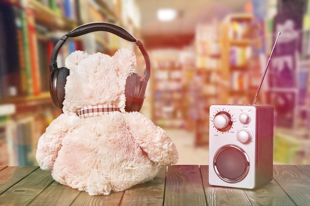 Oso de peluche con auriculares y radio en la mesa