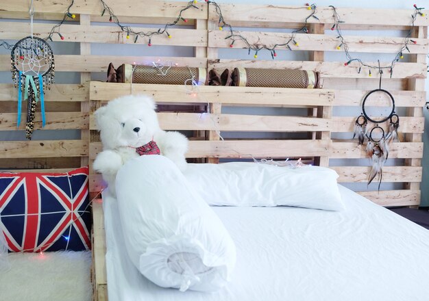 Oso de peluche blanco en una cama de madera.