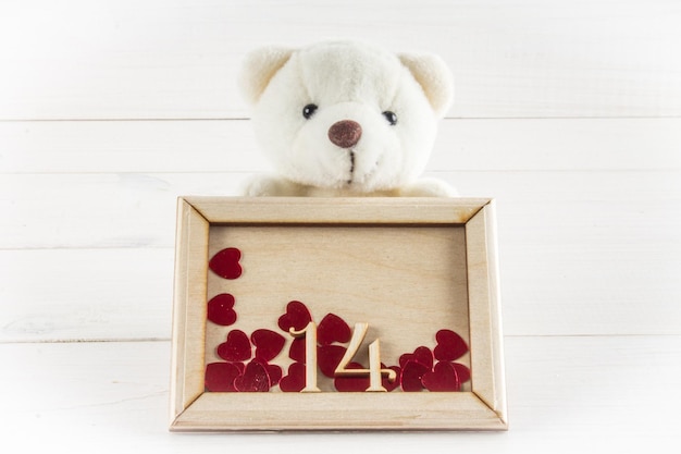 Foto oso de peluche blanco sujetando un plato con corazones concepto el 14 de febrero