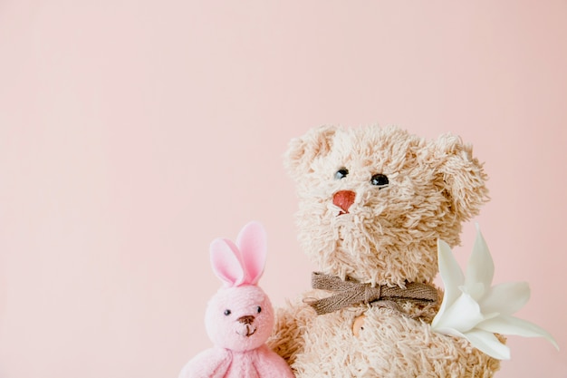 Oso de peluche y conejo con flor blanca